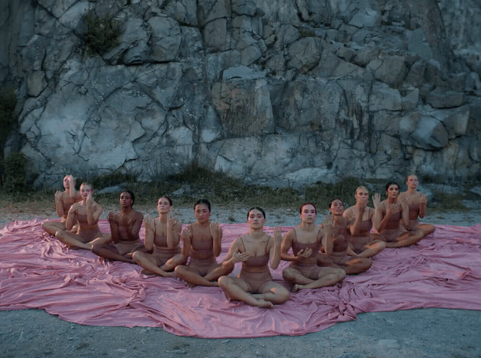 a group of naked men sitting on top of a pink blanket