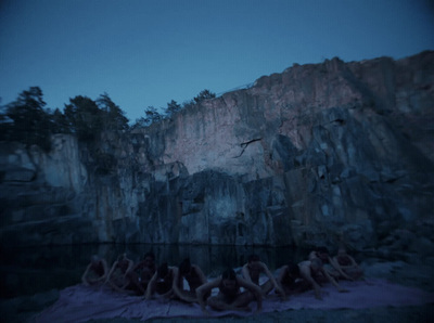 a group of naked people sitting in front of a mountain