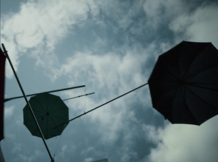 two umbrellas are hanging in the air against a cloudy sky