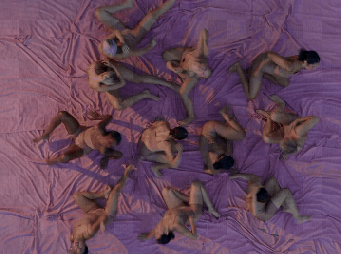 a group of naked men laying on top of a bed