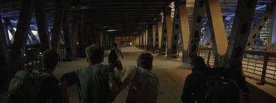 a group of people walking across a bridge at night