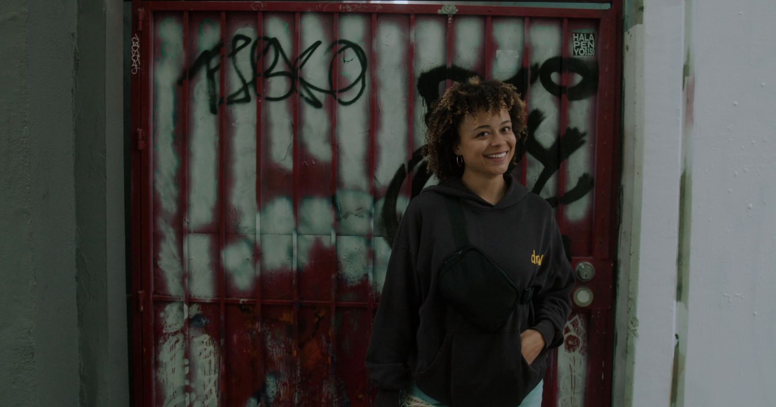 a woman standing in front of a door covered in graffiti