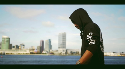 a man in a hoodie is standing by the water