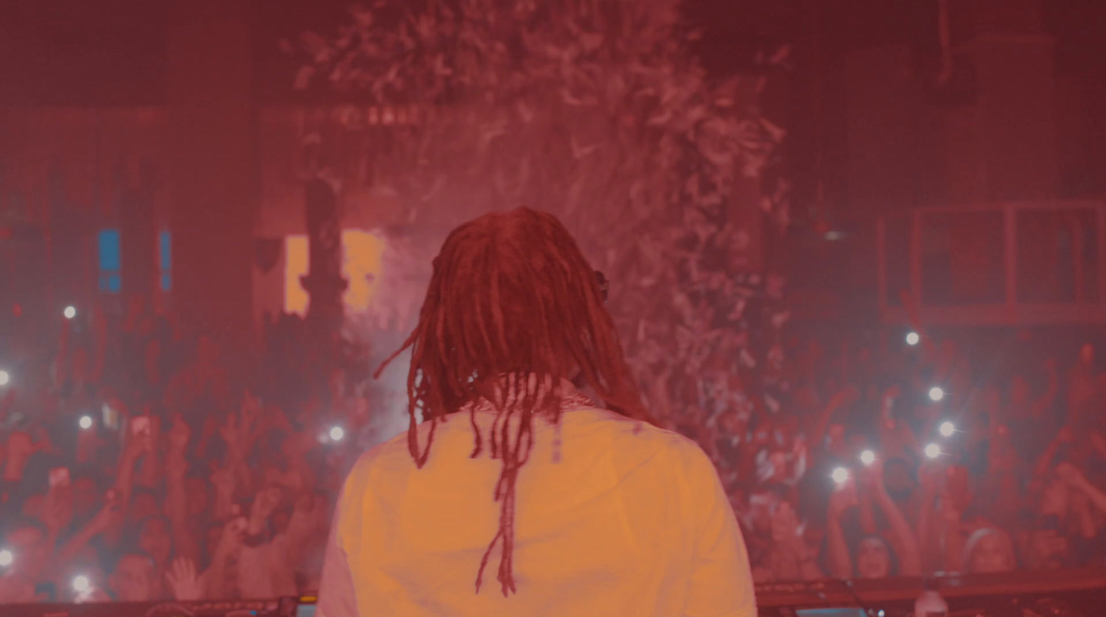 a man with dreadlocks standing in front of a crowd