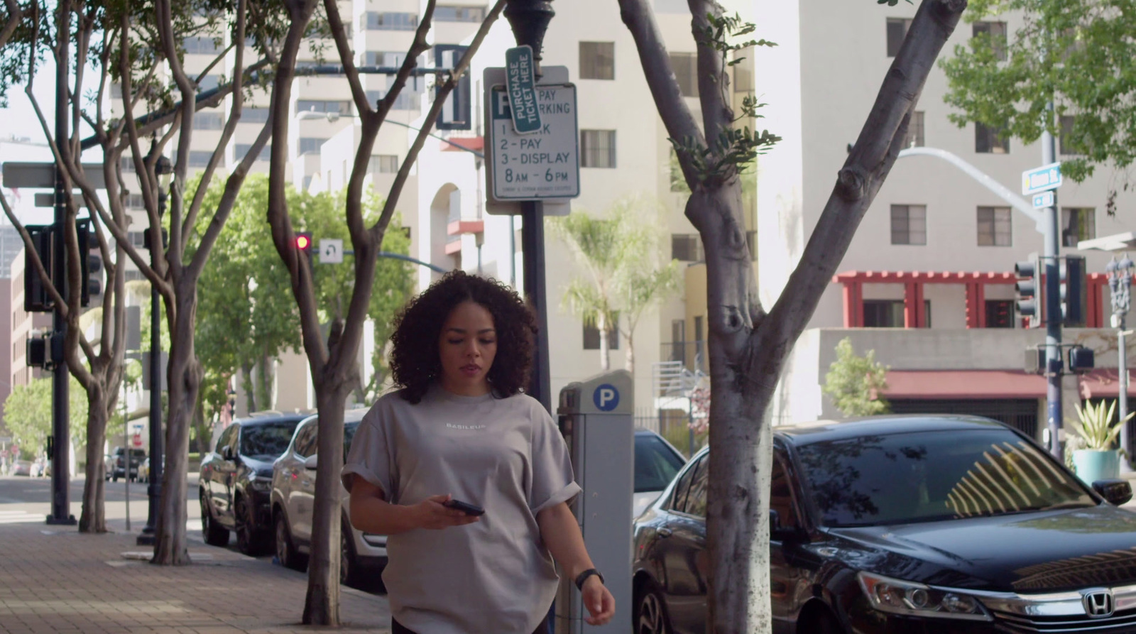 a woman walking down a sidewalk next to parked cars