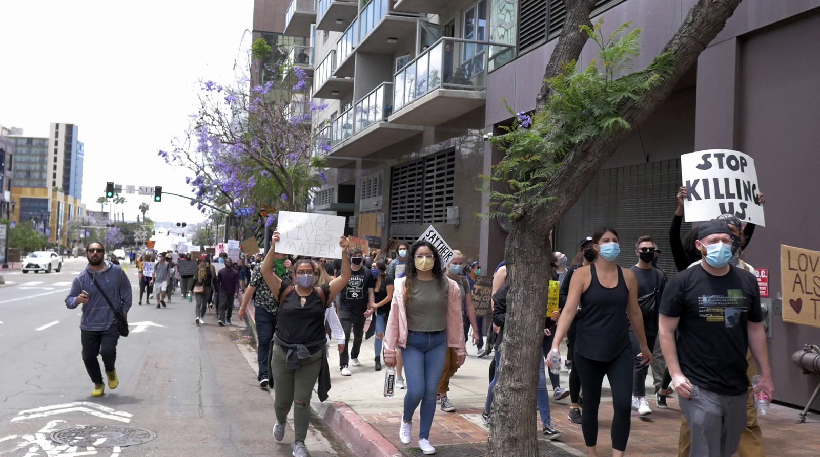 a group of people walking down a street holding signs