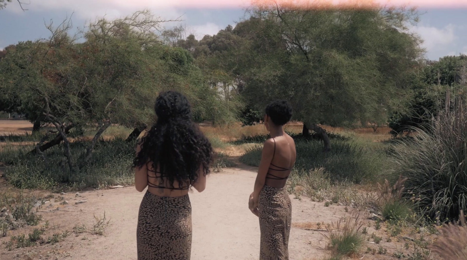 a couple of women standing on a dirt road