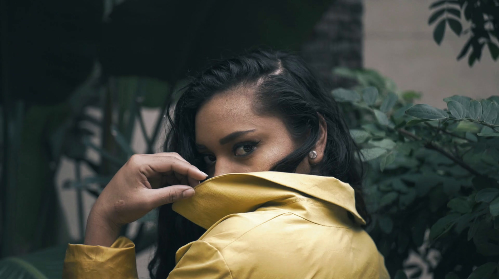 a woman in a yellow jacket is holding her coat over her face