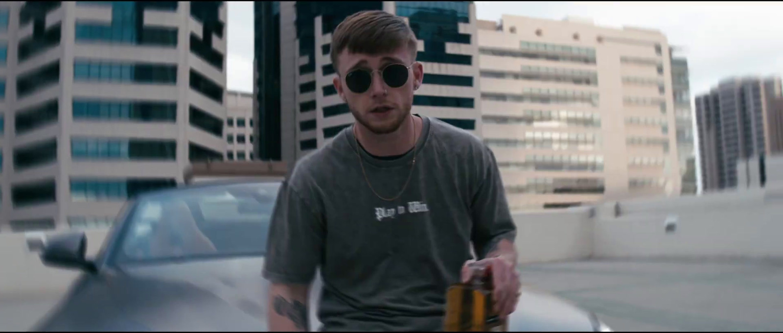 a man with sunglasses holding a bottle of beer