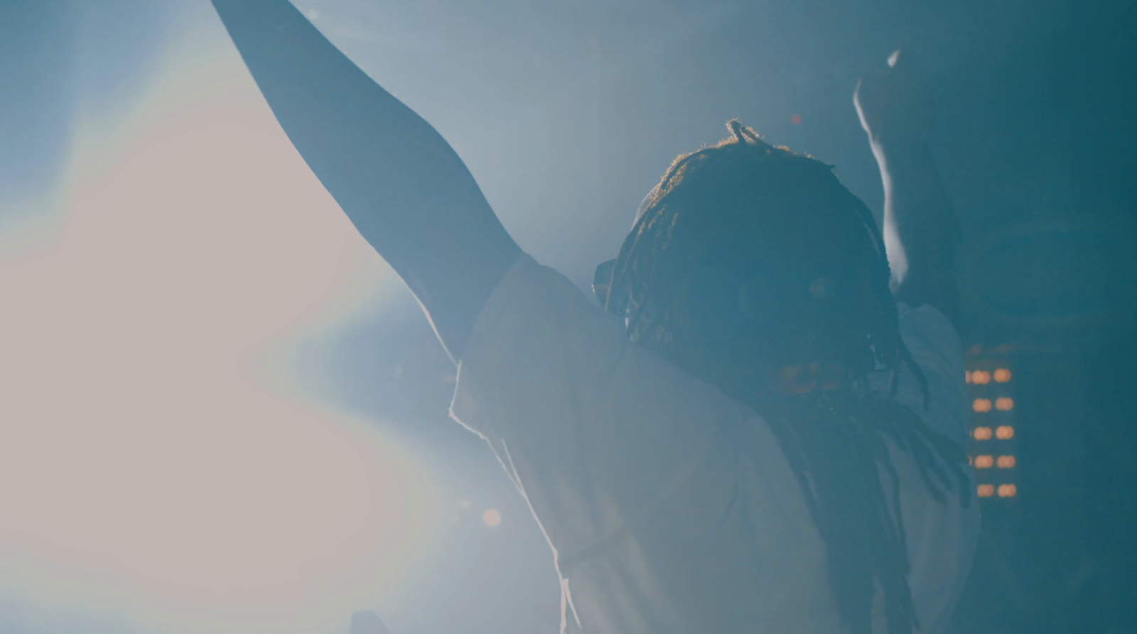 a man with dreadlocks holding his arms up in the air