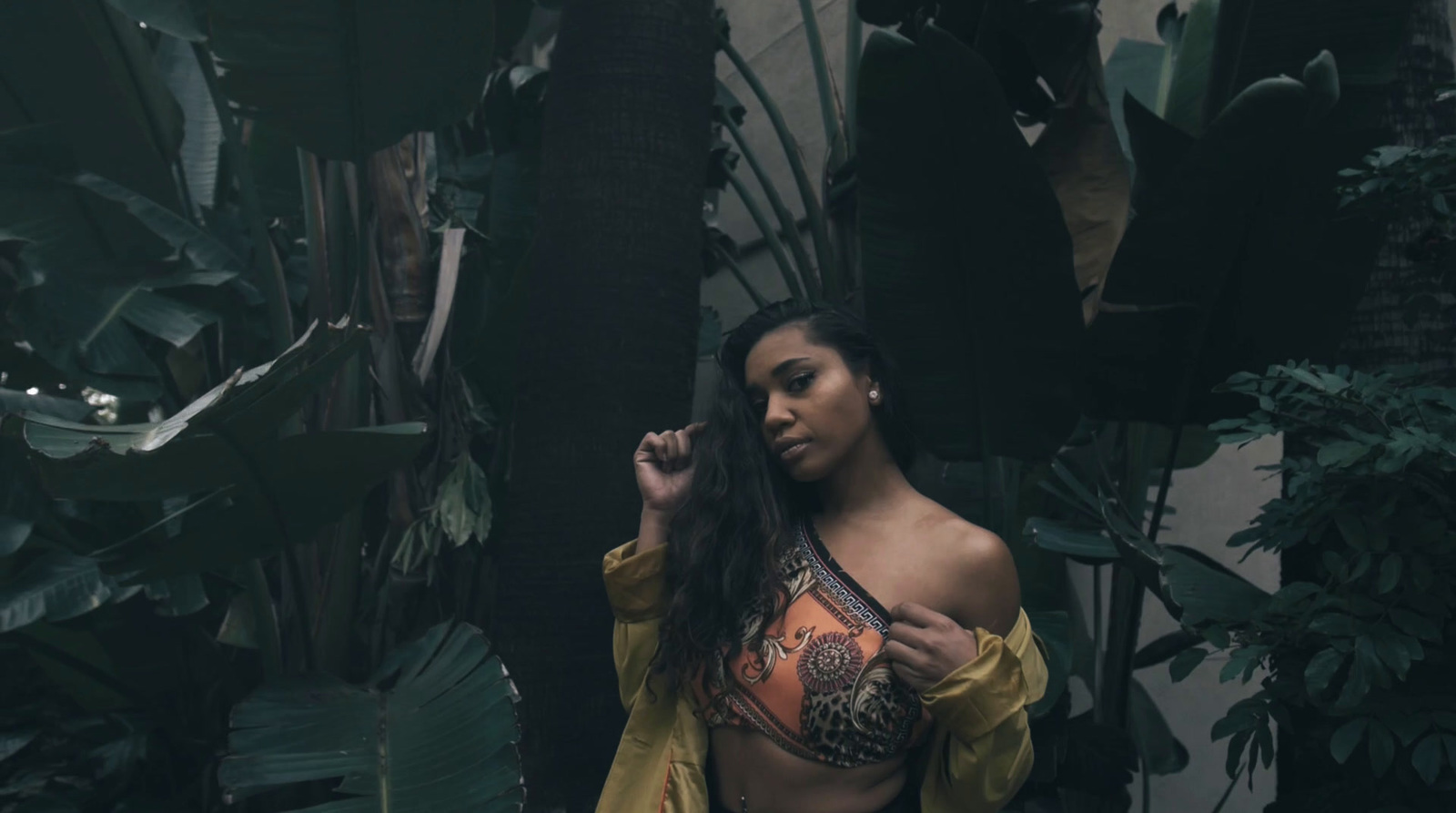 a woman in a yellow top standing in a jungle