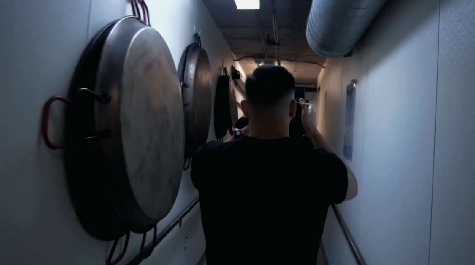 a man walking down a hallway next to a clock