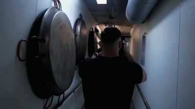 a man walking down a hallway next to a clock