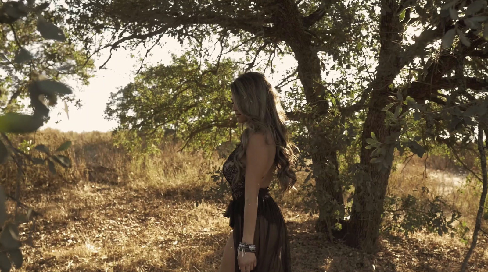 a woman in a black dress standing in a field