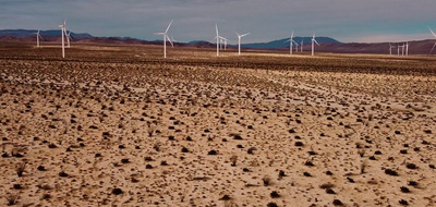 a large field of dirt with wind mills in the background