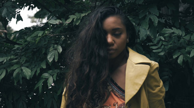 a woman with long hair standing in front of a tree