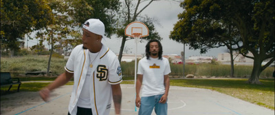 two men standing on a basketball court with trees in the background