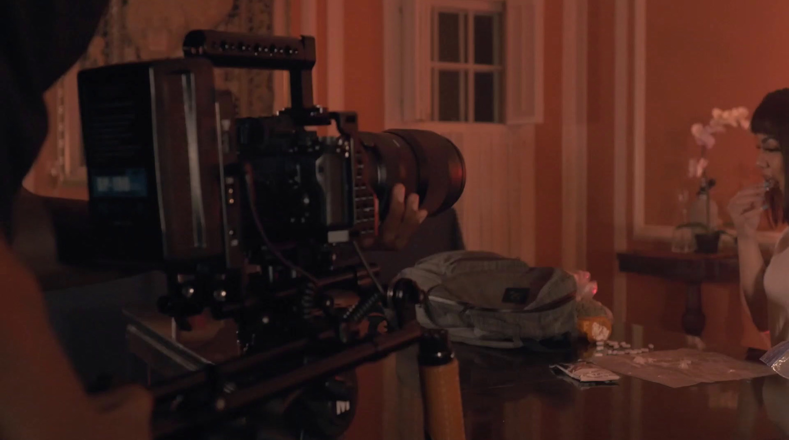 a woman sitting at a table in front of a camera