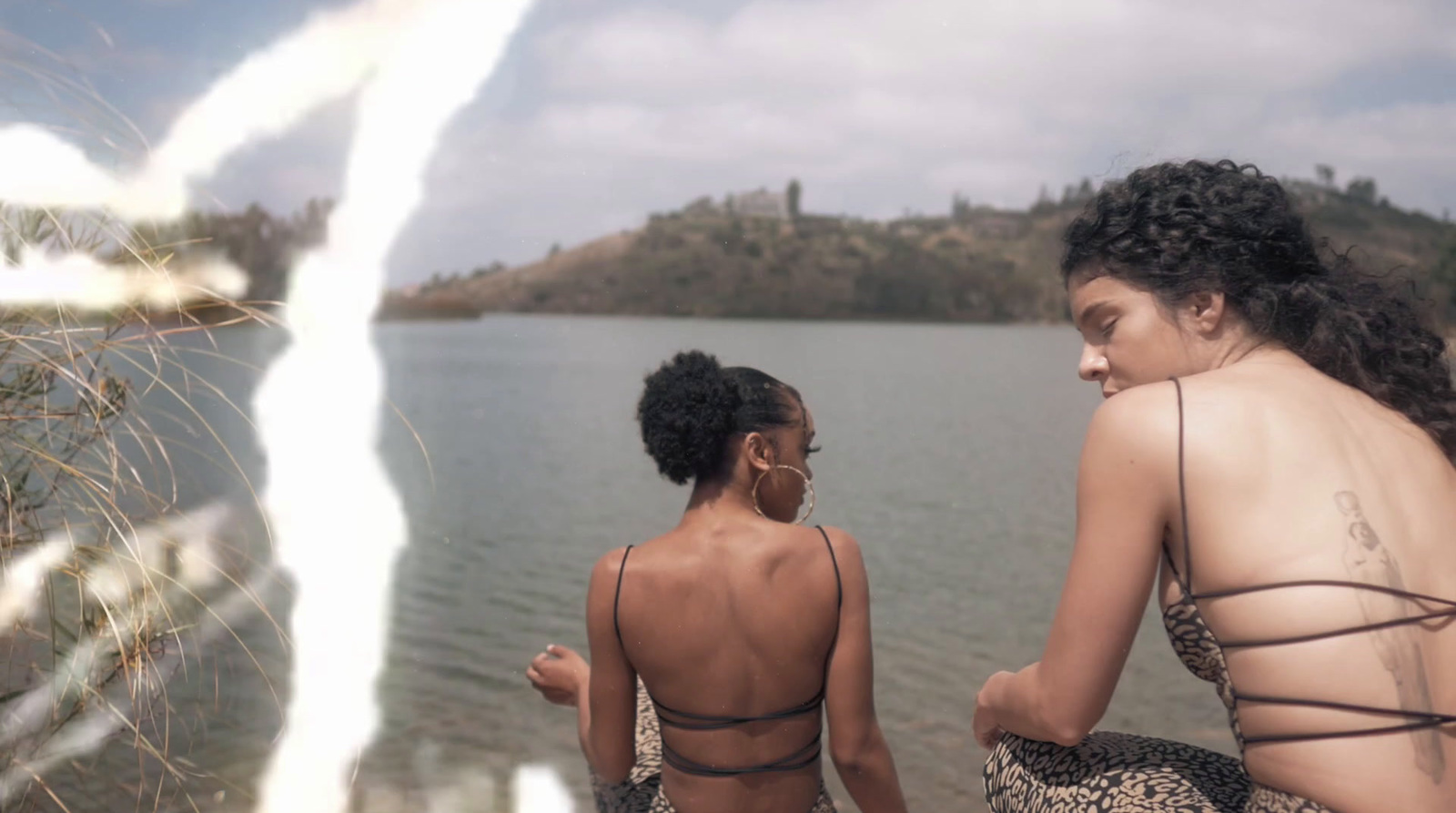 a couple of women sitting next to each other near a body of water