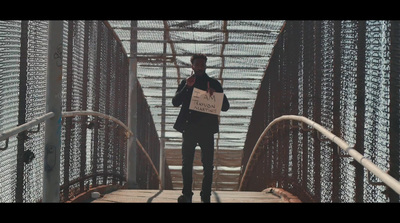 a man standing on a bridge holding a sign