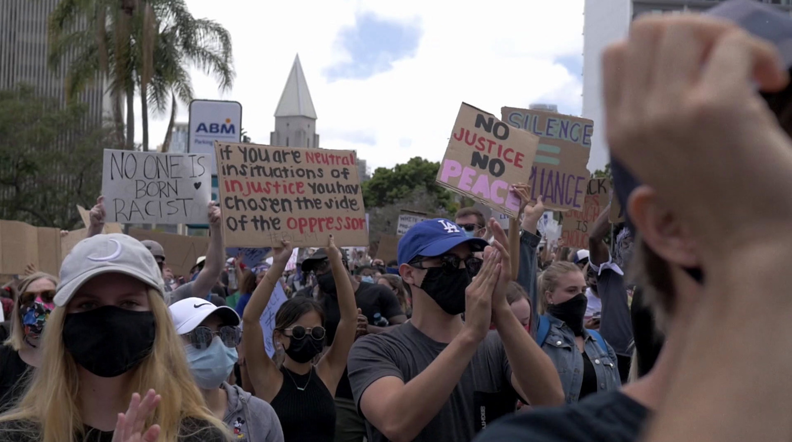 a group of people holding up signs and wearing masks