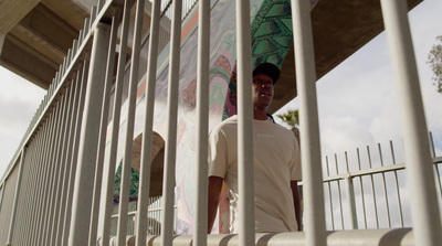 a man standing behind a fence holding a surfboard