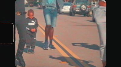 a woman walking down a street next to a little boy