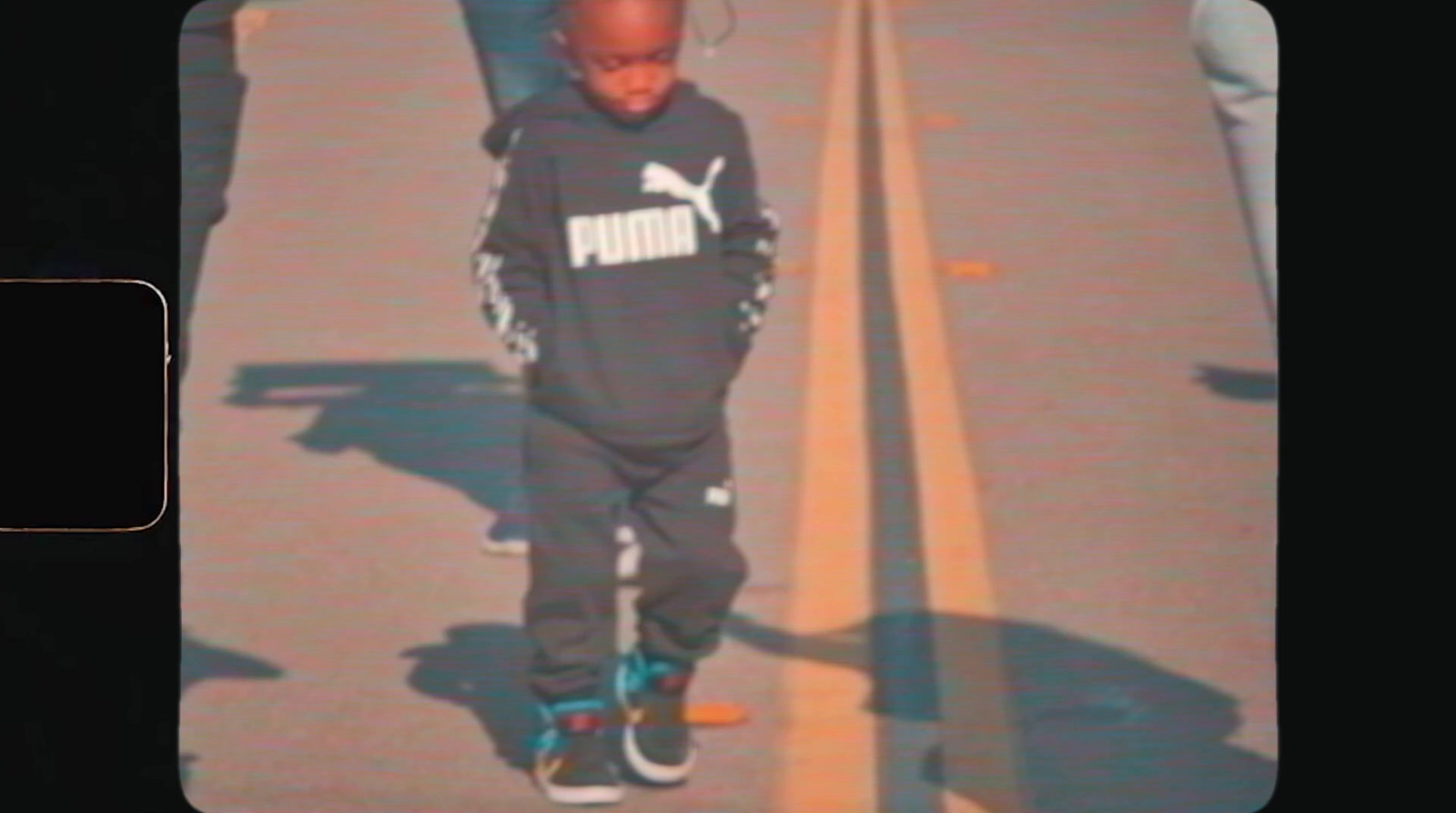 a little boy walking down a sidewalk next to a person