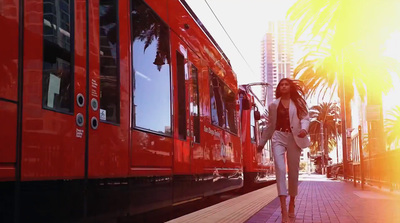 a woman walking down a sidewalk next to a red train