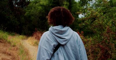 a woman walking down a path in the woods