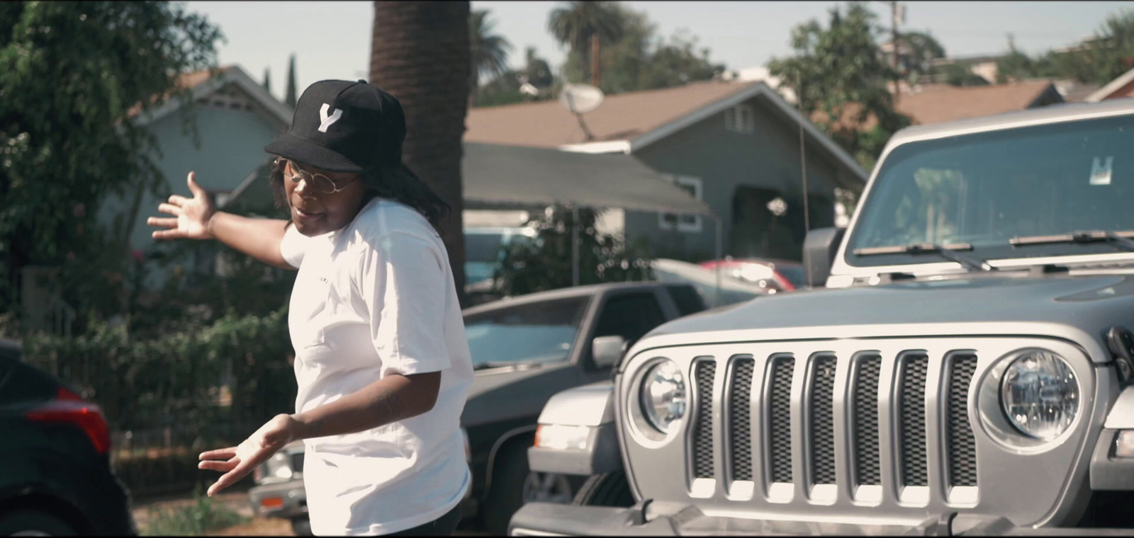 a man standing next to a gray jeep in a parking lot