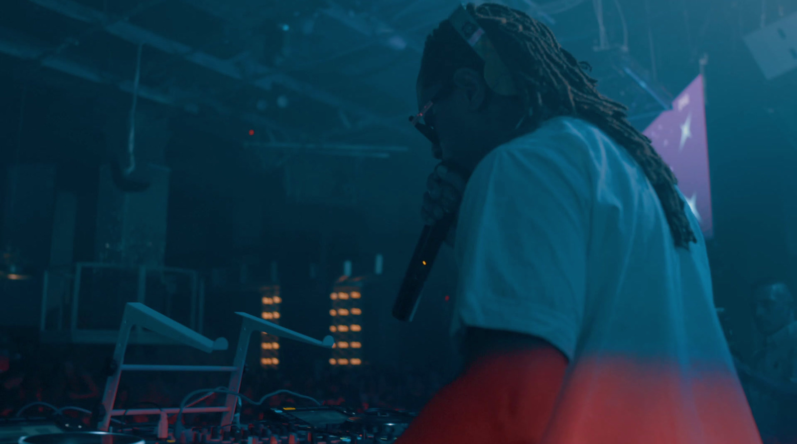 a man with dreadlocks standing in front of a dj set