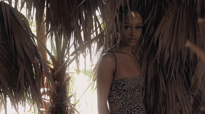 a woman standing in front of a palm tree