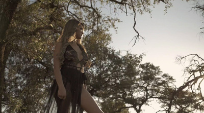 a woman in a black dress standing in a forest