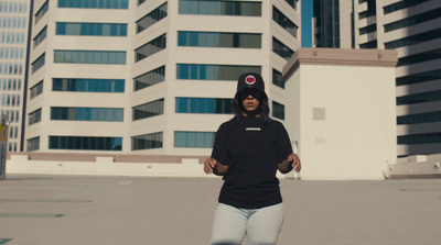 a woman standing in a parking lot with a building in the background