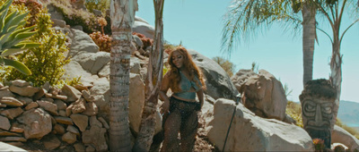 a woman standing in front of some rocks and palm trees