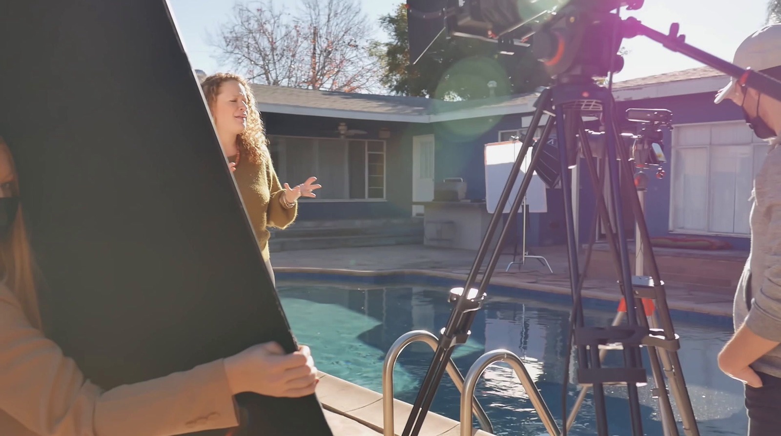 a woman standing in front of a camera next to a pool