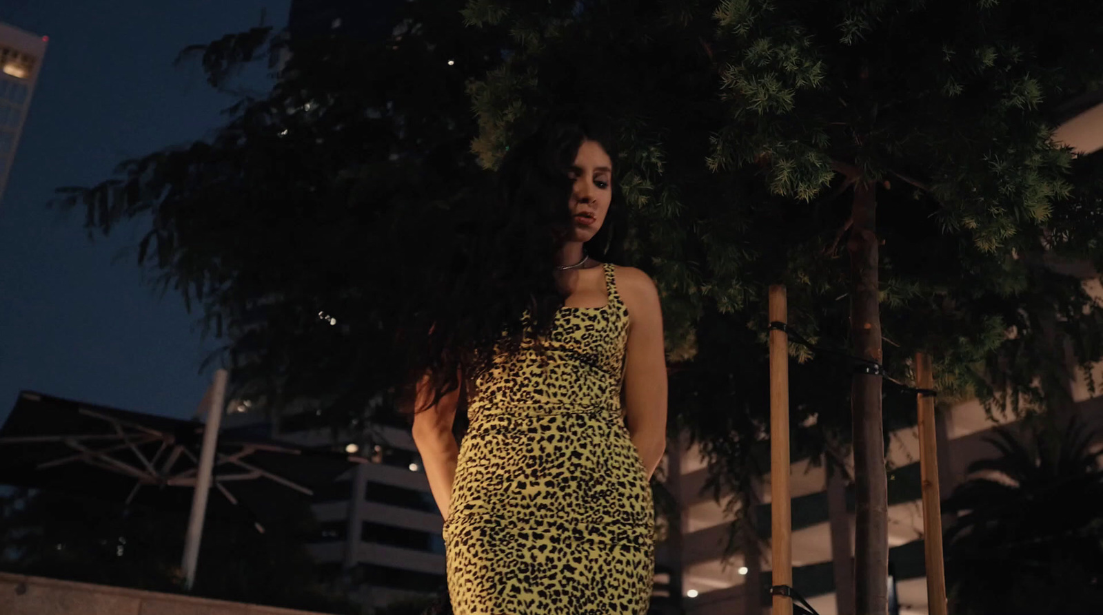 a woman in a yellow and black dress standing next to a tree