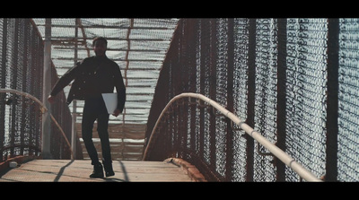 a man walking across a bridge holding a folder