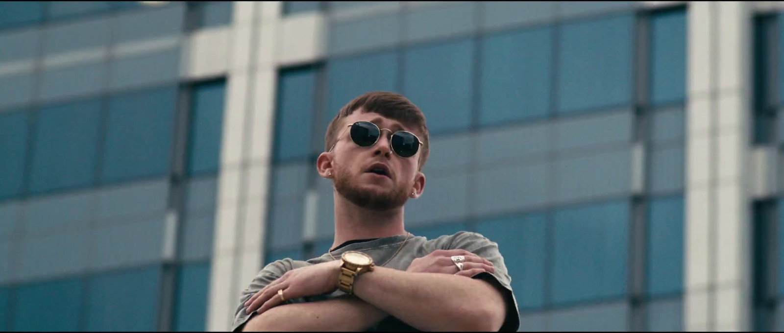 a man with his arms crossed standing in front of a building