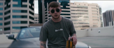 a man with sunglasses holding a bottle of beer