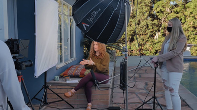 a woman sitting on a bench in front of a camera