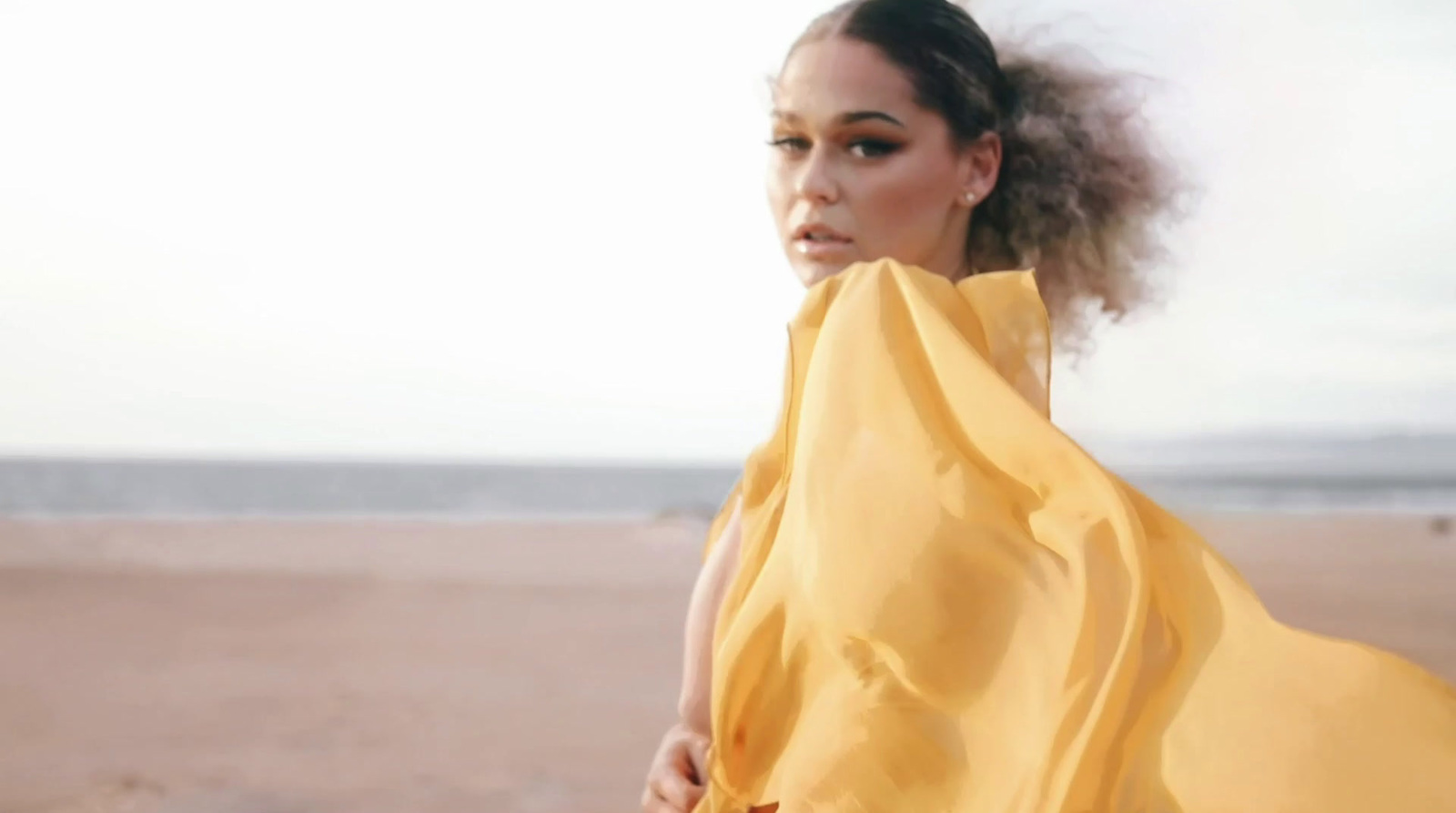 a woman in a yellow dress on the beach