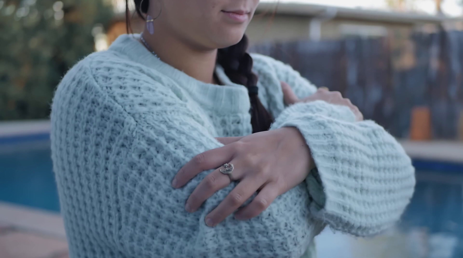 a woman in a sweater is standing near a pool