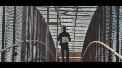 a man standing on a bridge with a sign in his hand