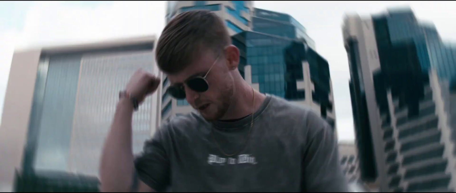 a man in a gray shirt talking on a cell phone