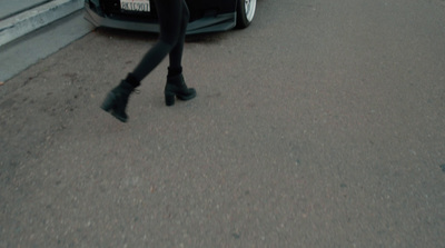 a woman walking down a street next to a car