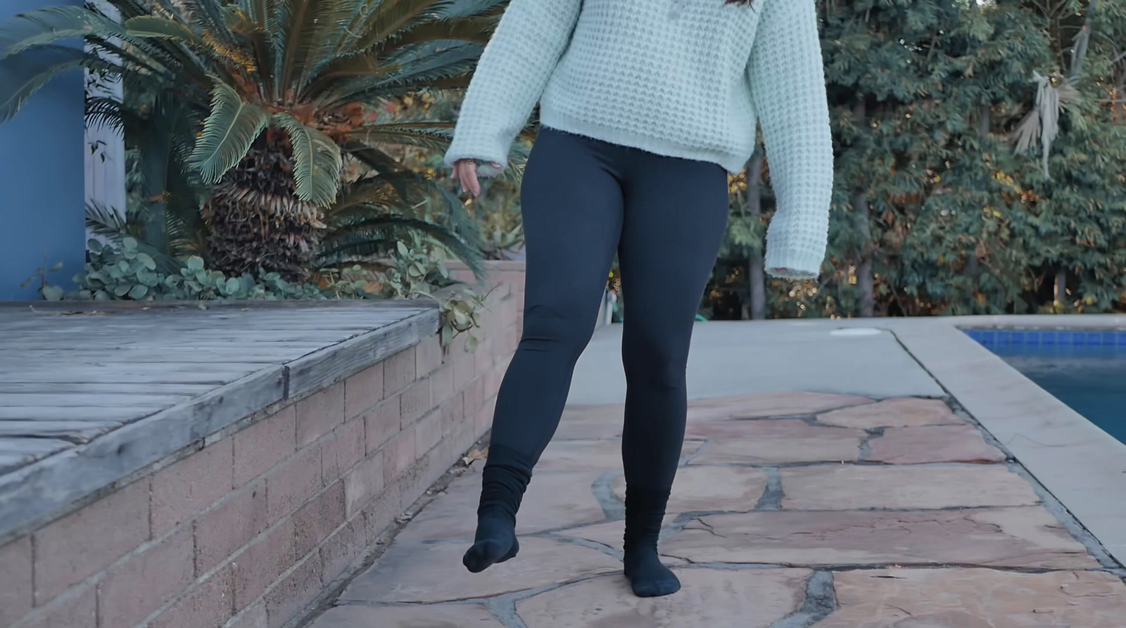 a woman walking down a sidewalk next to a pool