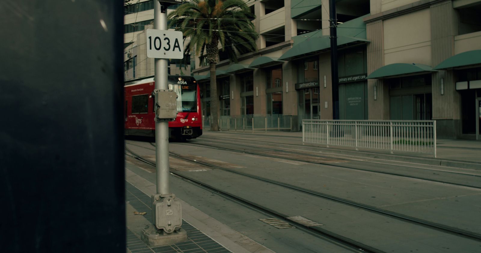 a red train traveling down train tracks next to a tall building