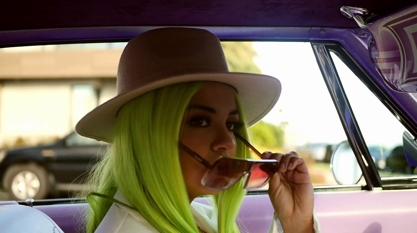 a woman with green hair and a fedora in a car